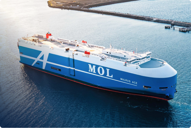 A large blue and white cargo ship named Walrus Ace, operated by MOL, sails near the coastline with docks and land in the background—an impressive scene capturing Media and Insights MOL in maritime action.