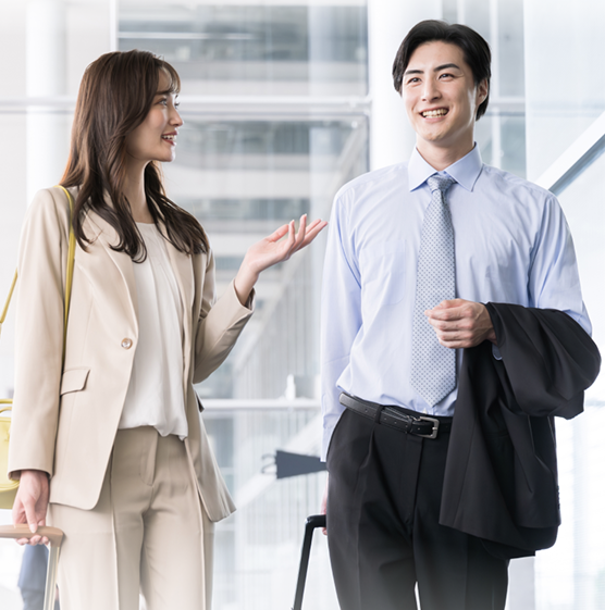 A man and woman in professional attire walk and converse in a modern office setting. The mood is friendly and engaged, with bright, natural lighting.