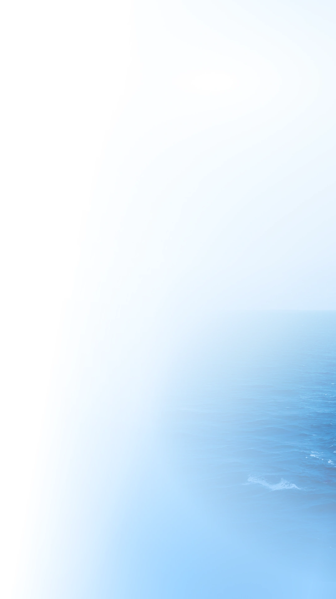 A calm, blue ocean fades into a white gradient on the left side, creating a peaceful and minimalistic seascape under a clear sky.